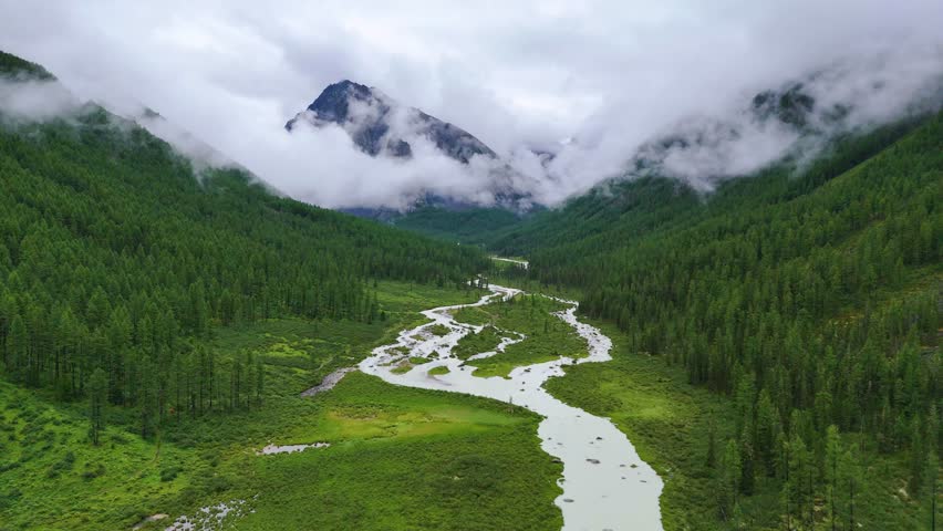 drone flight over the mountain river Shavla, cloud peaks in the clouds, Altai mountains
