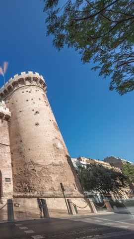 Towers of Quart timelapse hyperlapse in Valencia, Spain. Historical medieval gate, part of the ancient city walls. Popular landmark with a rich cultural heritage. Blue sky and street traffic scene.