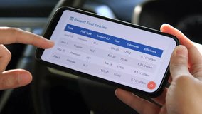 Closeup of a mans hands in a parked car using a dedicated expense tracker to analyze daily fuel costs and consumption statistics. This clip is perfect for content about vehicle ownership costs - Powered by Shutterstock - Get 15% off with code: PIKWIZARD15