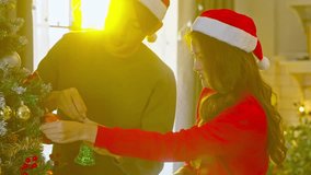 Asian Young couple decorating Christmas tree with ornament and warm sunlight creating joyful holiday atmosphere joyful Christmas couple decorating living room tree together with festive hats creating - Powered by Shutterstock - Get 15% off with code: PIKWIZARD15