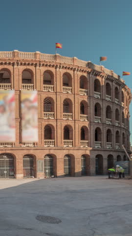 Panorama showing Bullring of Valencia (Plaza de Bous) timelapse and Bullfighting Museum, near Nord station. People walking around the historic amphitheater with a blue sky backdrop. Valencia, Spain.