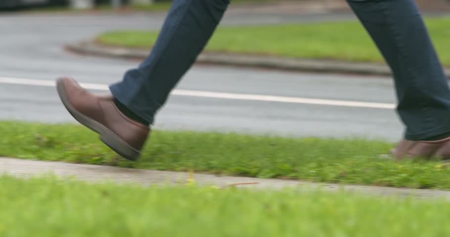 Man walking close up feet crossing from road to footpath sidewalk