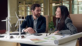 Multracial two ecology entrepreneurs Korean business woman Caucasian man laughing success gesture wind turbine model excited green energy project joyful office workers eco startup collaboration indoor - Powered by Shutterstock - Get 15% off with code: PIKWIZARD15