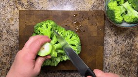 A head of broccoli is separated into florets using a knife against a wooden board. End grain cutting board made of oak. - Powered by Shutterstock - Get 15% off with code: PIKWIZARD15