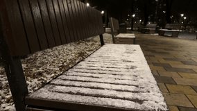 The first snow in a city park. Snow on a wooden bench outside. Snow on a park bench in the evening. Concept of the first snowfall in an urban setting - Powered by Shutterstock - Get 15% off with code: PIKWIZARD15