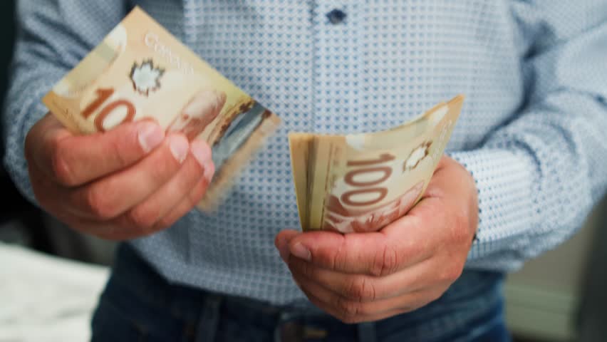 Canadian Dollar Banknotes In Male Hands Counting Money At Home. A Man Sits In Bedroom Counting His Canadian Dollars, Reflecting Financial Planning And Personal Economy.