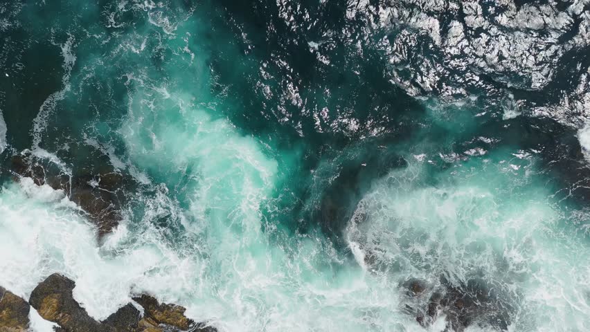 Top View Foamy Sea Waves Hitting Rocky Shoreline Aerial View Nova Scotia. Beautiful Top Down Drone Shot Showing The Power Of The Atlantic Ocean Waves Breaking On Coastal Reefs.