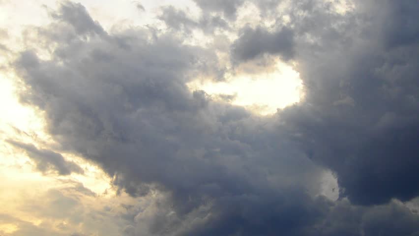 Time lapse of beautiful white clouds in sky. Volumetric light effect. Sunrays are hidden behind approaching dark cloud. Cumulus convection in troposphere. Cumulonimbus sunset and sunrays rapid motion