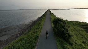 A cyclist rides along a coastal path beside the calm sea in Denmark, capturing an active lifestyle in a peaceful maritime landscape. - Powered by Shutterstock - Get 15% off with code: PIKWIZARD15