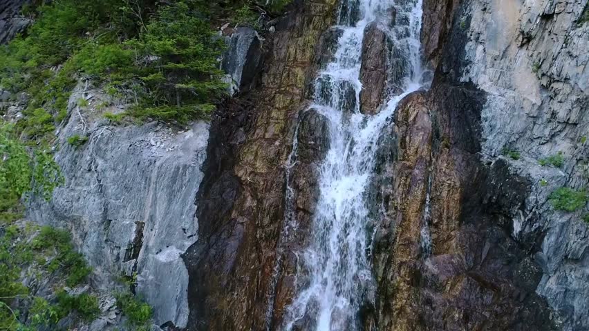 Aerial slow-motion view of a majestic waterfall, capturing flowing water, natural beauty, and serene landscape from above.