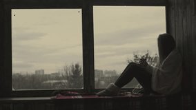 Sad woman looking out from a dark room through a brick window, capturing loneliness, contemplation, and emotional introspection in moody lighting. - Powered by Shutterstock - Get 15% off with code: PIKWIZARD15