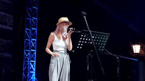 Young female singer performing on stage at night during a live concert - Powered by Shutterstock - Get 15% off with code: PIKWIZARD15