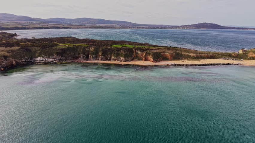 This captivating aerial view showcases the stunning coastline of Bulgaria with clear waters, sandy beaches, and rocky cliffs under a bright sky.