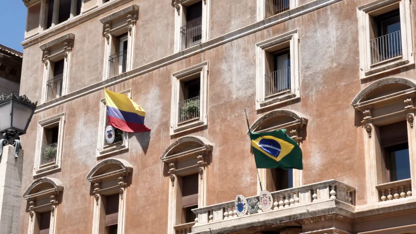 Colombian and Brazilian national flags waving outside a historic embassy or government building. Concept of diplomacy, international relations, foreign affairs, politics