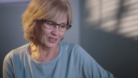 A close-up portrait of a smiling elderly woman with glasses in a softly lit room. - Powered by Shutterstock - Get 15% off with code: PIKWIZARD15