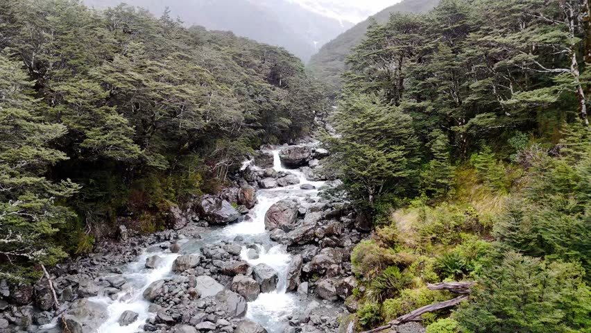 Low flying over a beautiful mountain river in the rain in New Zealand. Natural landscape. 