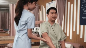 Asian middle-aged male patient is arms stretching, treated health recovery for shoulder muscle pain relief by a physical therapist doctor, passive medical therapy at massaging wellness spa clinic. - Powered by Shutterstock - Get 15% off with code: PIKWIZARD15