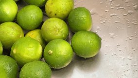Fresh green limes gathered on a stainless-steel surface, with water droplets on both the limes and the surrounding area, giving a clean and refreshing appearance - Powered by Shutterstock - Get 15% off with code: PIKWIZARD15