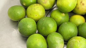 Fresh green limes gathered on a stainless-steel surface, with water droplets on both the limes and the surrounding area, giving a clean and refreshing appearance - Powered by Shutterstock - Get 15% off with code: PIKWIZARD15