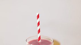 Pink smoothie in clear glass, striped straw, bright lighting, slow upward camera movement, minimal background - Powered by Shutterstock - Get 15% off with code: PIKWIZARD15