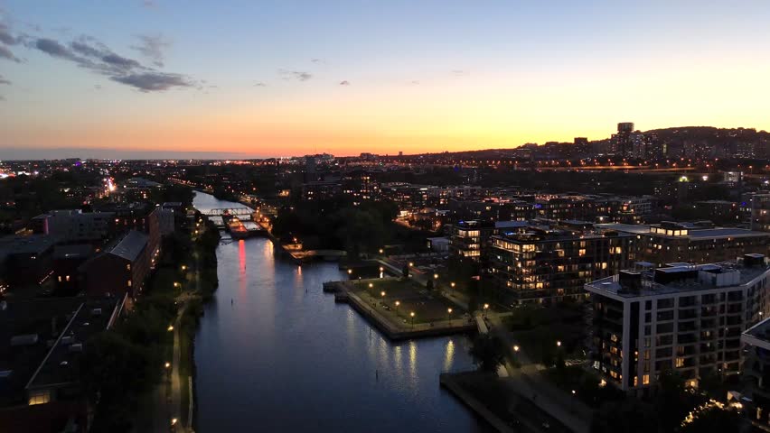 Montreal skyline at dusk, city lights reflecting over water in Grifintown and downtown. g.