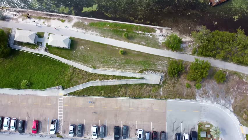 Top-down aerial drone shot of the Seven Mile Bridge Vista Point parking lot in the Florida Keys, capturing a smooth rotating view over cars, shoreline, and the iconic bridge