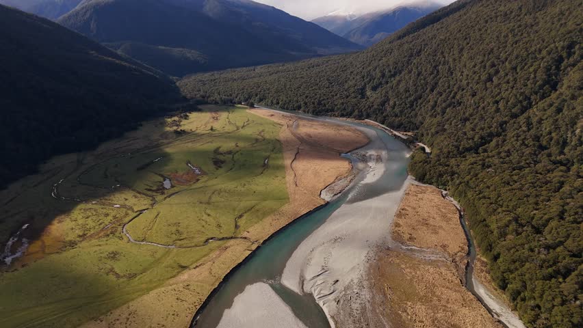 River winding through valley in Mount Aspiring National Park, South Island, New Zealand. Aerial backward