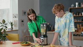 Teen siblings standing at kitchen counter, making smoothie for first time, opening blender container and checking result smelling it - Powered by Shutterstock - Get 15% off with code: PIKWIZARD15