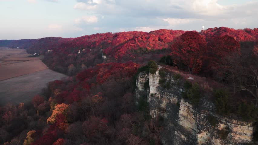 A drone shot flying along the cliffs at Salt Lick Point, Illinois. People can be seen on the scenic lookout and the forest below is bathed in autumnal colors.