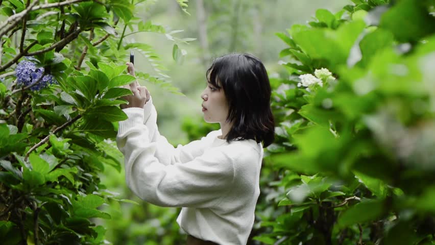 Attractive girl taking pictures of flowers outdoors