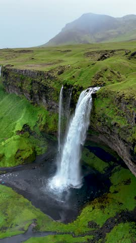 Seljalandsfoss waterfall cascades gracefully over rugged cliffs in Icelands lush greenery.