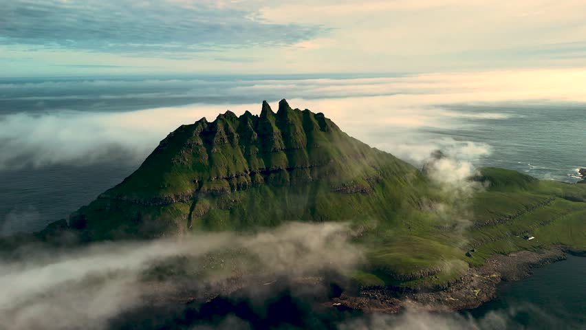 Explore the stunning Drangarnir peaks in the Faroe Islands, where rugged cliffs rise dramatically from the sea, shrouded in mystical fog. A breathtaking view of natures artistry awaits.