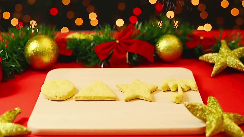 Powdered sugar being sprinkled over homemade gingerbread Christmas cookies shaped with decorative holiday patterns — festive seasonal baking with a playful twist.