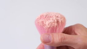 A finger shakes powder from a pink makeup brush.Close up. - Powered by Shutterstock - Get 15% off with code: PIKWIZARD15