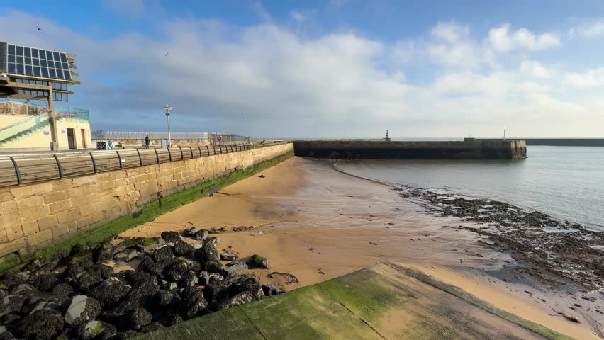 Right panning video at Seaham Harbour in the UK as morning fog recedes and sun shines through sea clouds.