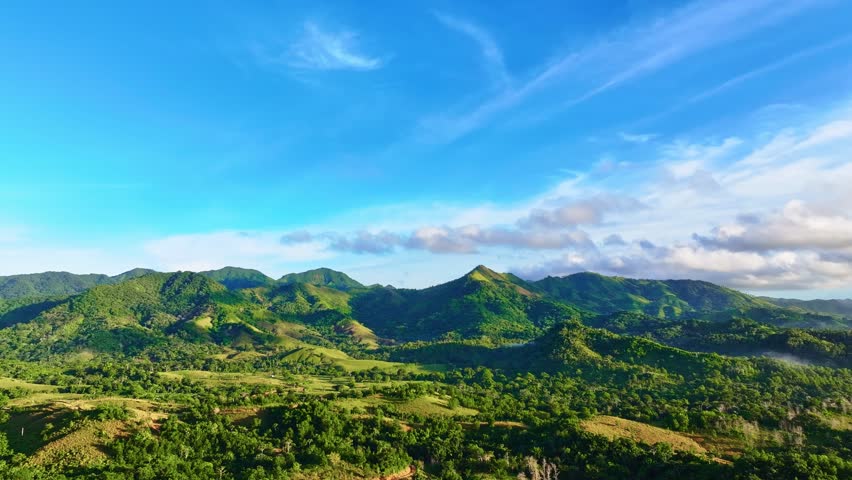 Natural landscape of mountain peaks against a skyline. Palm jungle on mountain hills. Adventure travel concept. Green mountains with grassy hills and blue sky on a summer day.