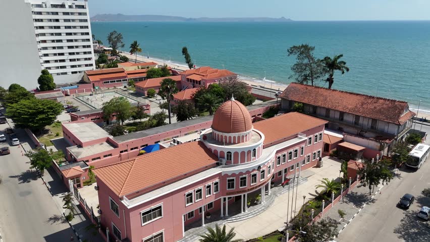 Aerial top view of Benguela coastline, Angola, with beach activity, small boats, and clear green sea under bright daylight in a warm African setting