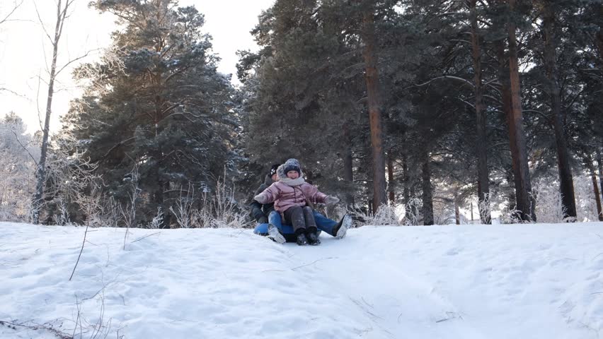 Grandmother with granddaughter having fun on the toboggan hill, laughing. Humor, young at heart. Family having fun outdoors in winter on sledge . Family winter time. Recreational pursuit