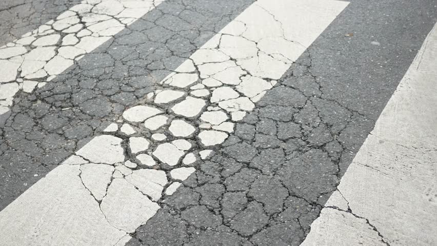 Cracked crosswalk in urban setting shows signs of neglect