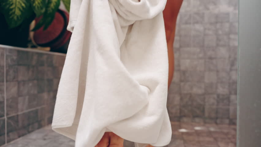 Woman Stepping onto Bath Mat with Wet Feet After Shower Wearing White Towel, Close-Up Low Angle of Feet and Tile Floor, Cleanliness and Routine Concept.
