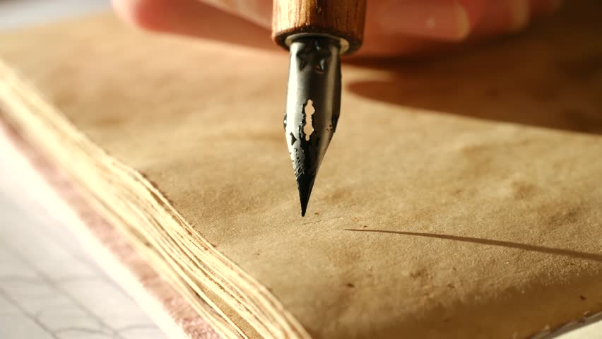 Close up shot person hand writing the word hello with black ink using vintage dip pen. Calligrapher is working on aged, yellowed paper under warm, natural sunlight. Calligrapher writing the word hello