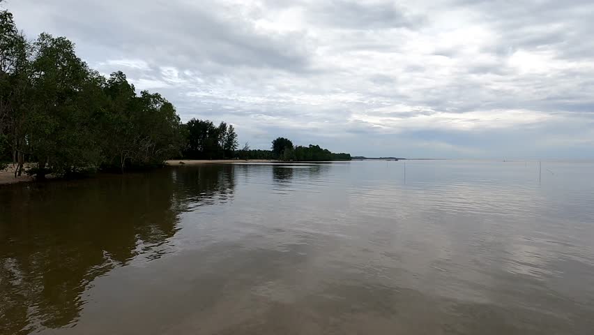 Calm Coastal Shoreline Under Cloudy Sky