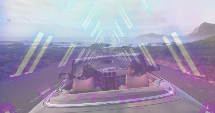 Passenger turning and raising arm causing driver raising arms cheering coast auto neon tracing arms. Convertible, roadtrip, seaside, shoreline, couple, travel, cinematic