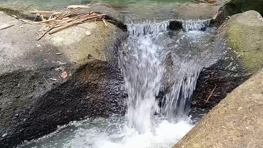 Splashes of river water flowing from the gaps in the rocks 