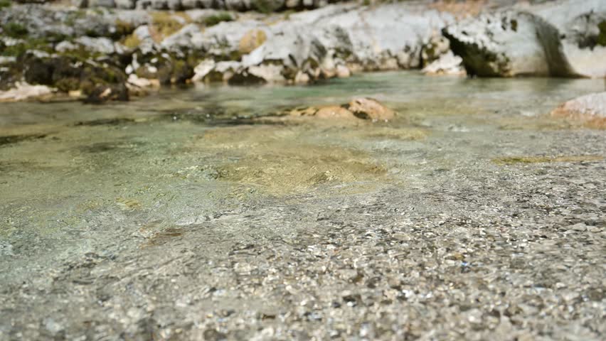 Rippled surface of a clear mountain creek with flowing water creating natural abstract patterns. 4K with selective focus.