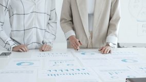 Two businesswomen examining financial data on charts and graphs during an office meeting, highlighting collaboration and strategy, close up. Business people concept - Powered by Shutterstock - Get 15% off with code: PIKWIZARD15