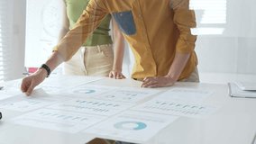 Professional team collaborating, reviewing financial documents and graphs on laptop with printed data spread across conference table in contemporary workspace. Business people concept - Powered by Shutterstock - Get 15% off with code: PIKWIZARD15