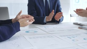 Businesspeople team clapping hands in meeting celebrating success with financial charts, data analysis, sales growth reports, and teamwork achievement in modern office. Business handshake - Powered by Shutterstock - Get 15% off with code: PIKWIZARD15