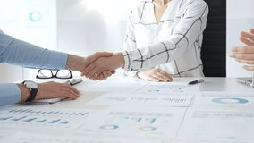 Business partners shaking hands in office with financial charts, laptop and reports on table, symbolizing success, teamwork, agreement, collaboration and corporate growth. Businesspeople handshake - Powered by Shutterstock - Get 15% off with code: PIKWIZARD15