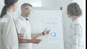 Businessman presenting data analysis and marketing strategy on a whiteboard while collaborating with colleagues in an office meeting. Business people concept - Powered by Shutterstock - Get 15% off with code: PIKWIZARD15